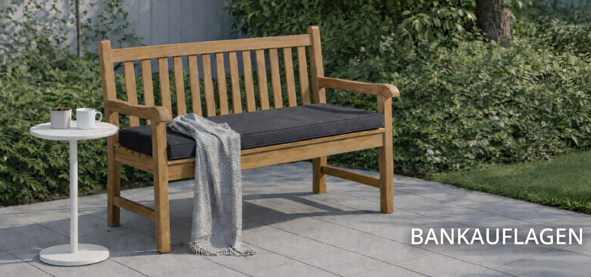 Eine Holz Gartenbank mit anthraziter Bankauflage auf Terrasse im Garten mit weißem Beistelltisch